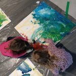 dwoje dzieci maluje planszę