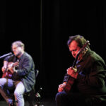 dwóch mężczyzn gra na gitarze na scenie