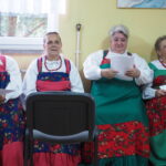 4 kobiety w strojach udowych siedzą i śpiewają