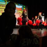 dzieci ogądają występ tańczących dziewczyn z pomponami