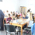 dzieci siedzą przy stołach malują farbkami