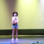 dziewczynka stoi na scenie z mikrofonem