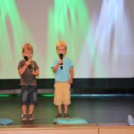 de och chłopców stoi na scenie z mikrofonem