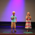 chłopiec i dziewczynka na scenie z mikrofonem