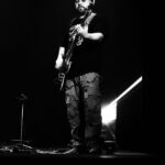 czarno- białe zdjęcie przedstawiające mężczyznę stojącego z gitara.