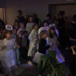 dzieci w przebraniach aniołków i dorośli stojący w budynku