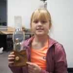 dziewczynka trzyma wykonaną przez siebie lampę naftową