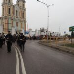 grupa ludzi stojących na drodze przed kościołem