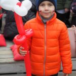 chłopiec z pomalowana twarzą trzyma w ręku balon biało czerwony