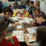dzieci siedzą przy stołach kolorują obrazki