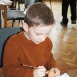 zdjęcie przedstawia chłopca malującego pisankę