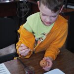 zdjęcie przedstawia chłopca malującego pisankę