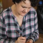 zdjęcie przedstawia kobietę malującą woskiem pisankę
