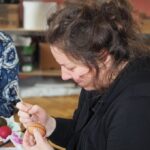 zdjęcie przedstawia kobietę malującą woskiem pisankę