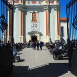 zdjęcie przedstawia motocykle i ludzi chodzących wokół w tle kościół