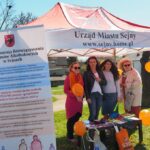 zdjęcie przedstawia 4 kobiety pod namiotem Urząd Miasta Sejny oraz baner Miejska Komisja Rozwiązywania Problemów Alkoholowych