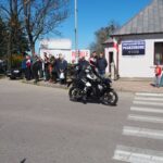 jadący motocykle i na chodniku stoją ludzie