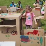 kobiety, dziewczynki i chłopcy malują farbami po kartonach