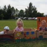 3 dziewczynki siedzą w kartonach pomalowanych na kolorowo