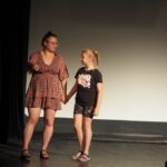 kobieta i dziewczynka stoją na scenie trzymając się za ręce