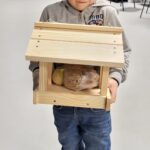 chłopiec trzymający karmnik z pokarmem dla ptaków