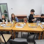 dzieci siedzące przy stole na którym leży jedzenie