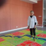 kobieta stoi na kolorowych planszach leżących na podłodze w budynku